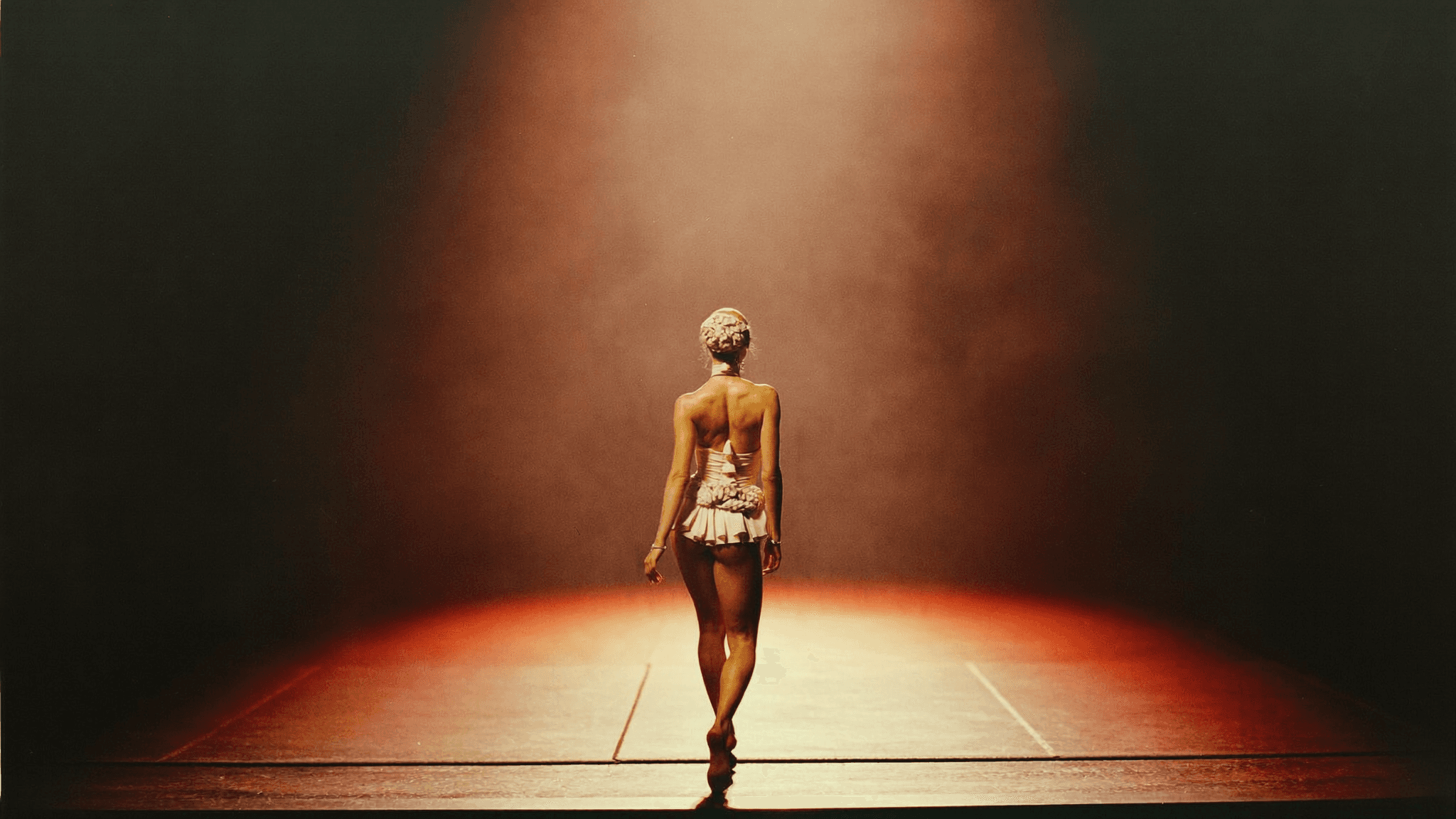 A female physique athlete stepping onto a competition stage