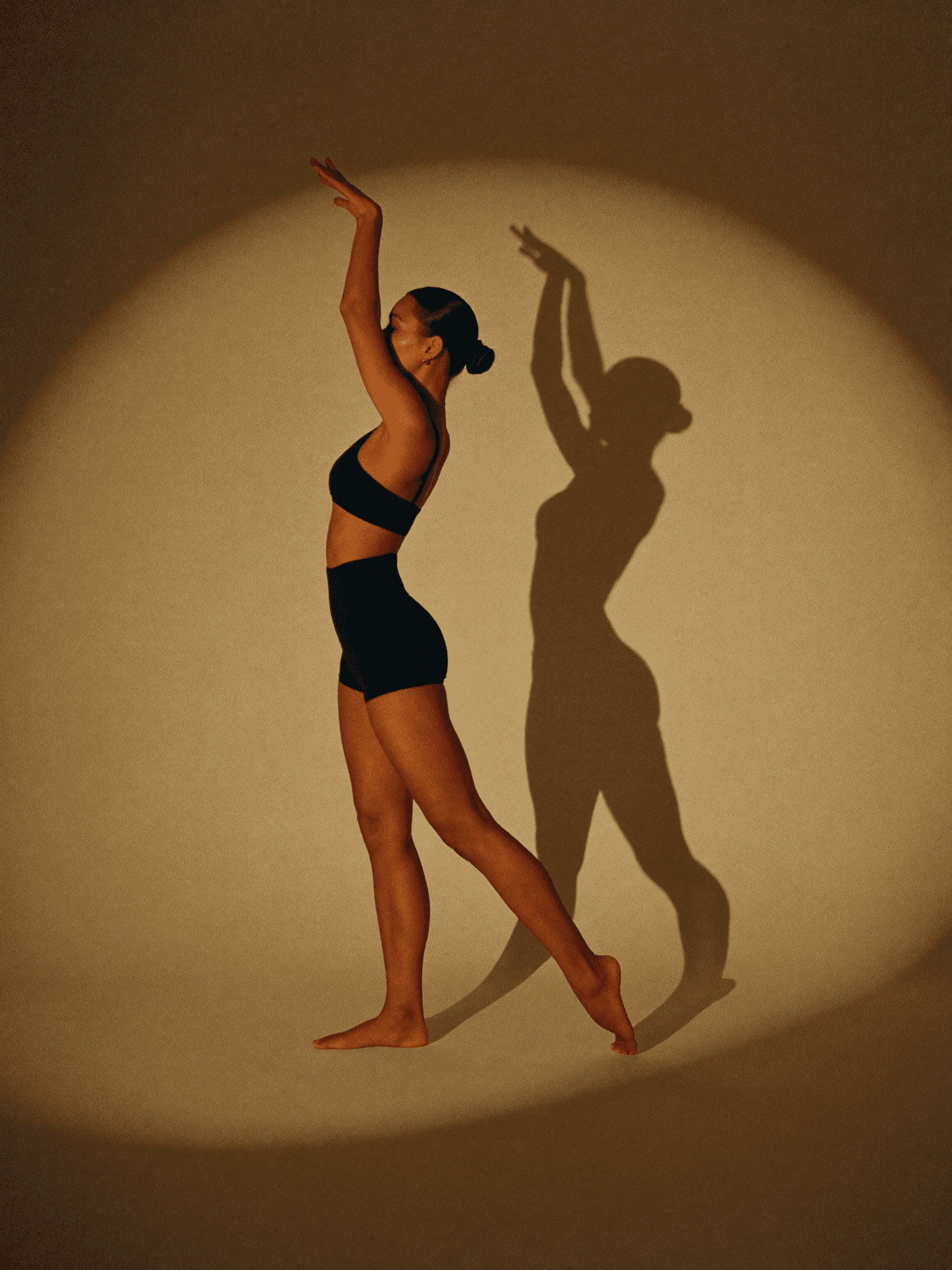 A woman practising stage posing in a warm studio